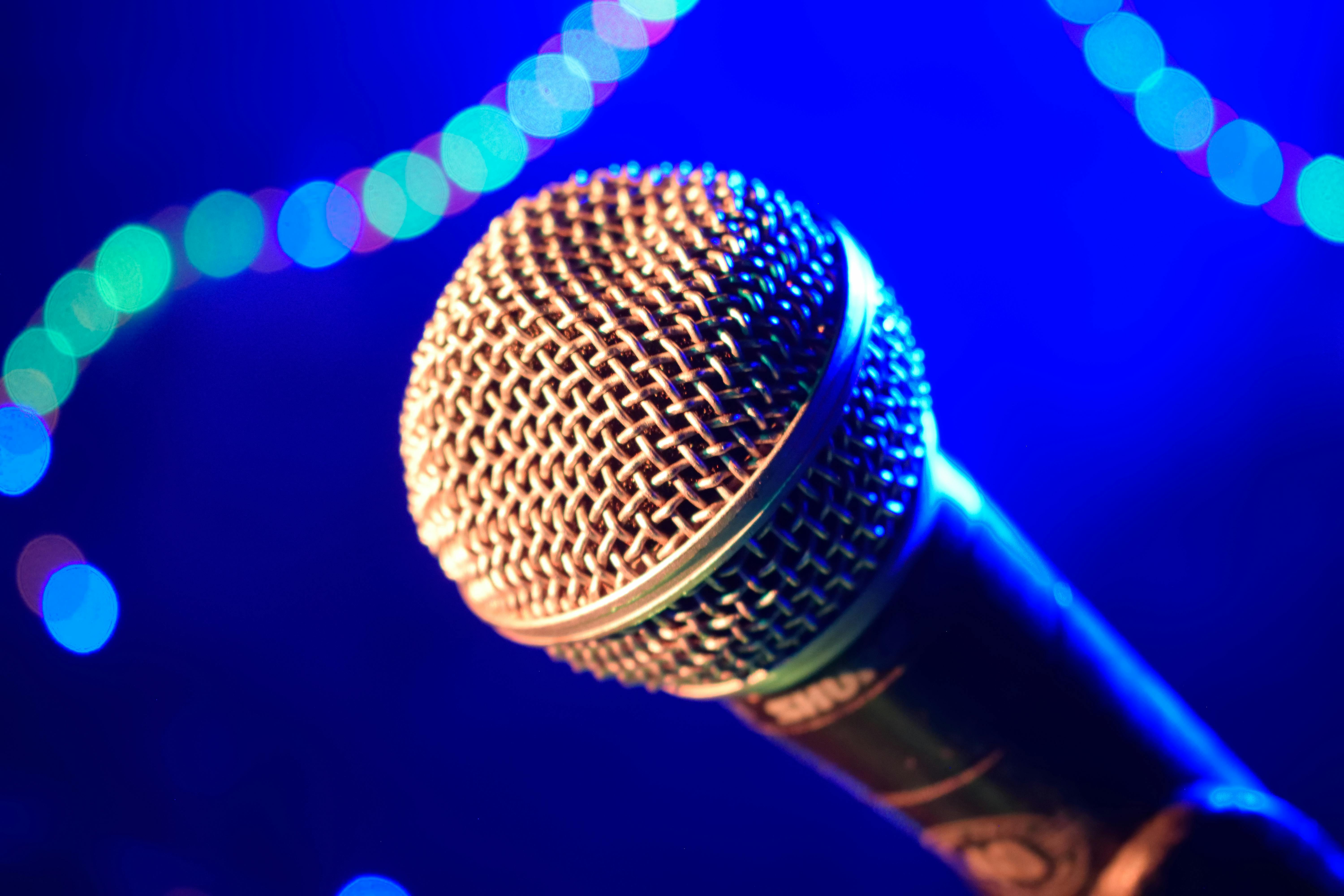 Close-up of a microphone against a vibrant blue bokeh background, perfect for music and performance themes.